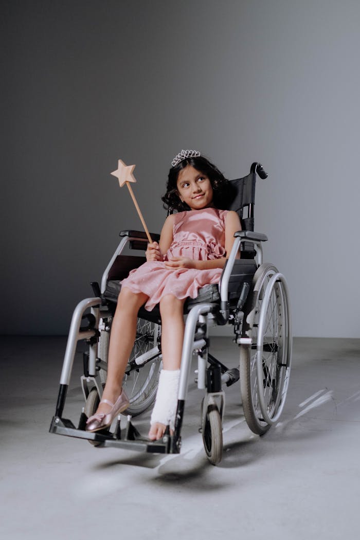 Charming girl smiling in a wheelchair with magic wand and tiara, symbolizing joy and resilience.
